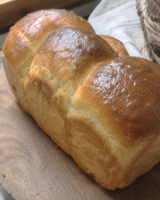 Brioche tressée dorée posée sur un linge, photographiée dans une lumière douce.