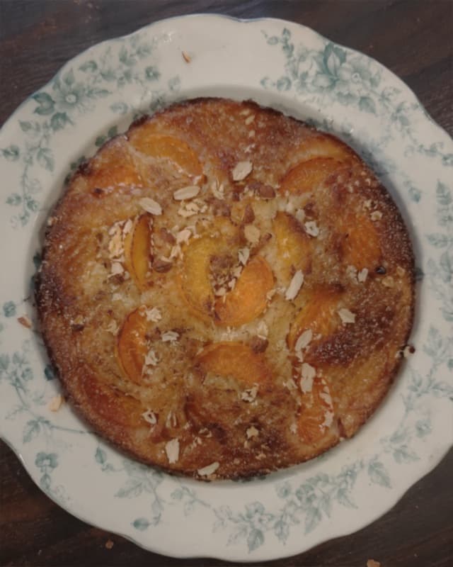 Gâteau rond aux fruits dorés photographié du dessus dans une assiette à motifs.
