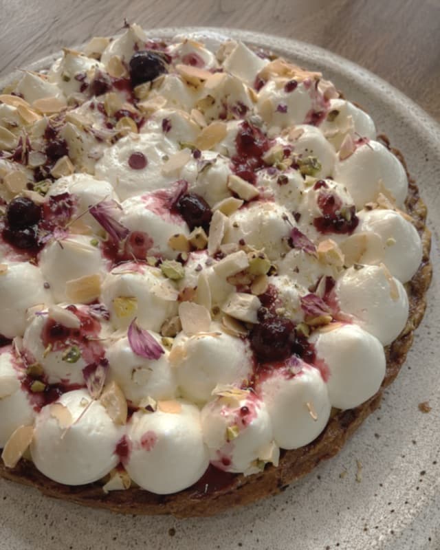 Tarte décorée de touches de crème blanche et de fruits, photographiée sur une assiette.